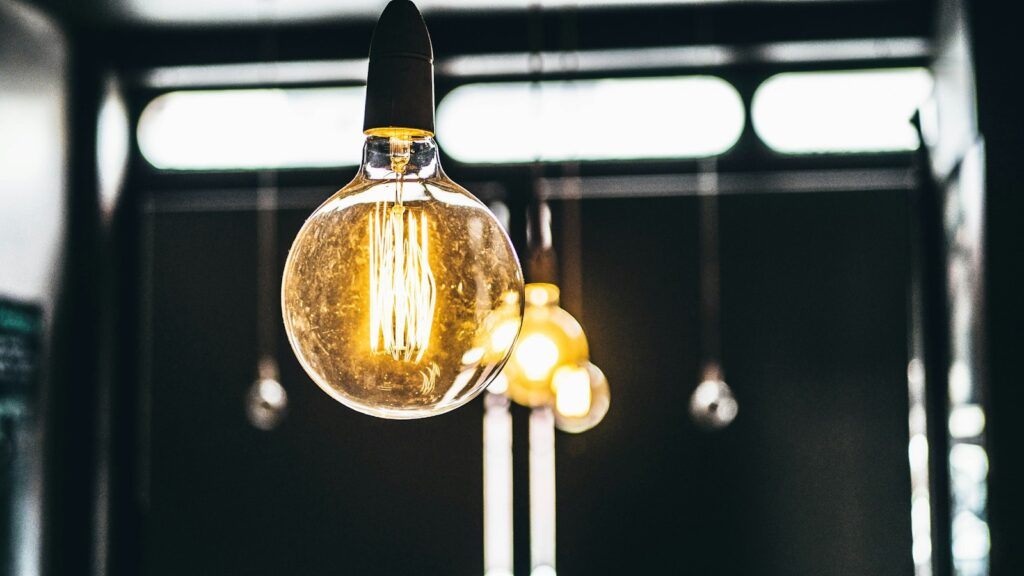 Glowing filament light bulb hanging from a ceiling