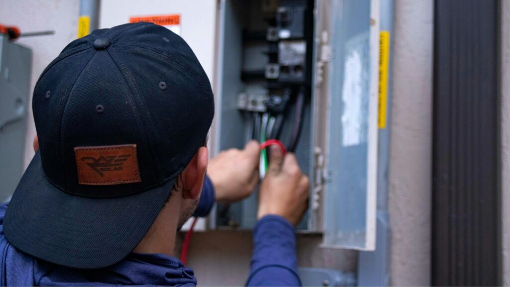 Worker wiring a breaker inside an open electrical panel
