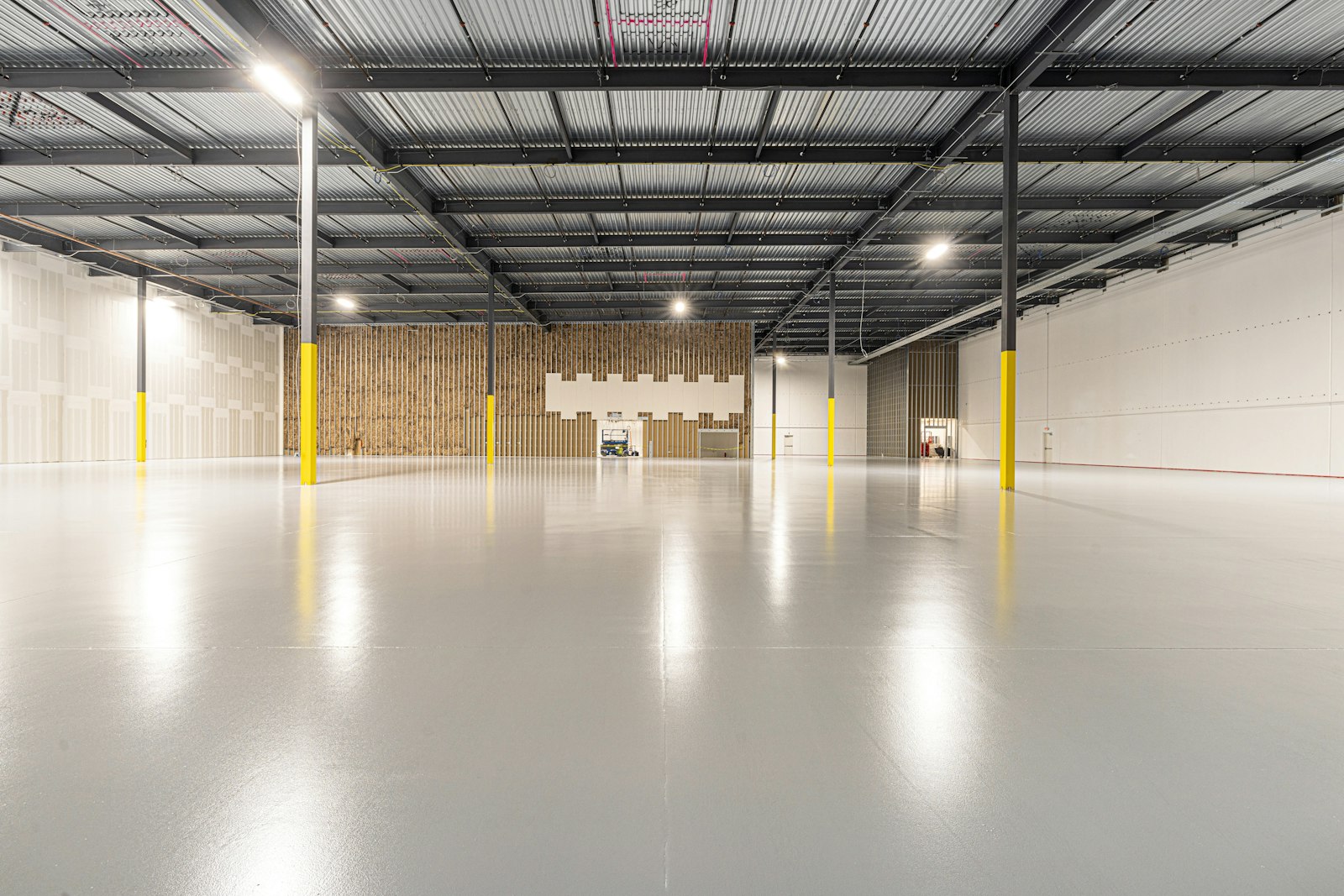 Empty warehouse lit by overhead LED high bay lights - Electrician Abilene - Electrician Abilene Empty warehouse lit by overhead LED high bay lights