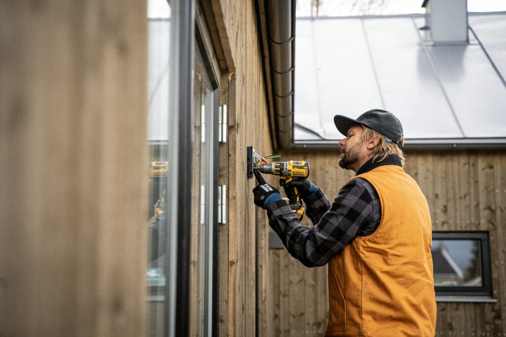 Worker using a cordless drill on an exterior wall
